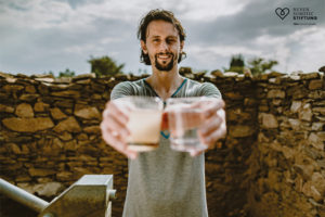 Neven Subotic hält zum Vergleich zwei Wassergläser in die Kamera. Sauberes aus dem neuen Brunnen und trübes aus verunreinigter Quelle.